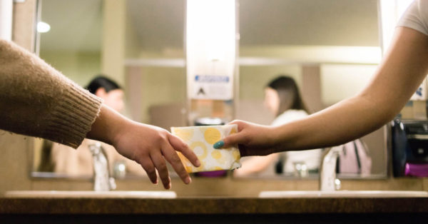 Period Poverty - a person giving another a sanitary towel